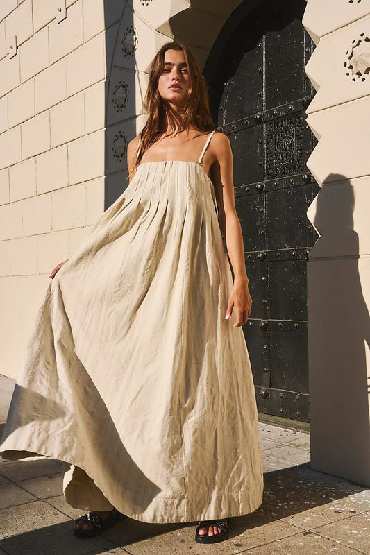  Modelo usando vestido de algodão bege com alças finas e caimento fluido, perfeito para dias quentes de verão.