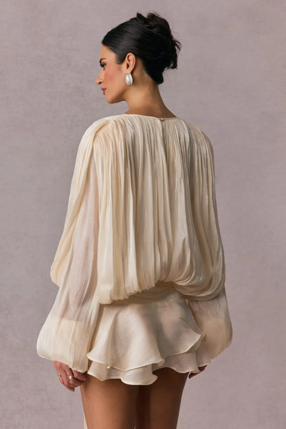 Vestido Celestine bege com mangas longas plissadas e detalhe fluido visto traseiro