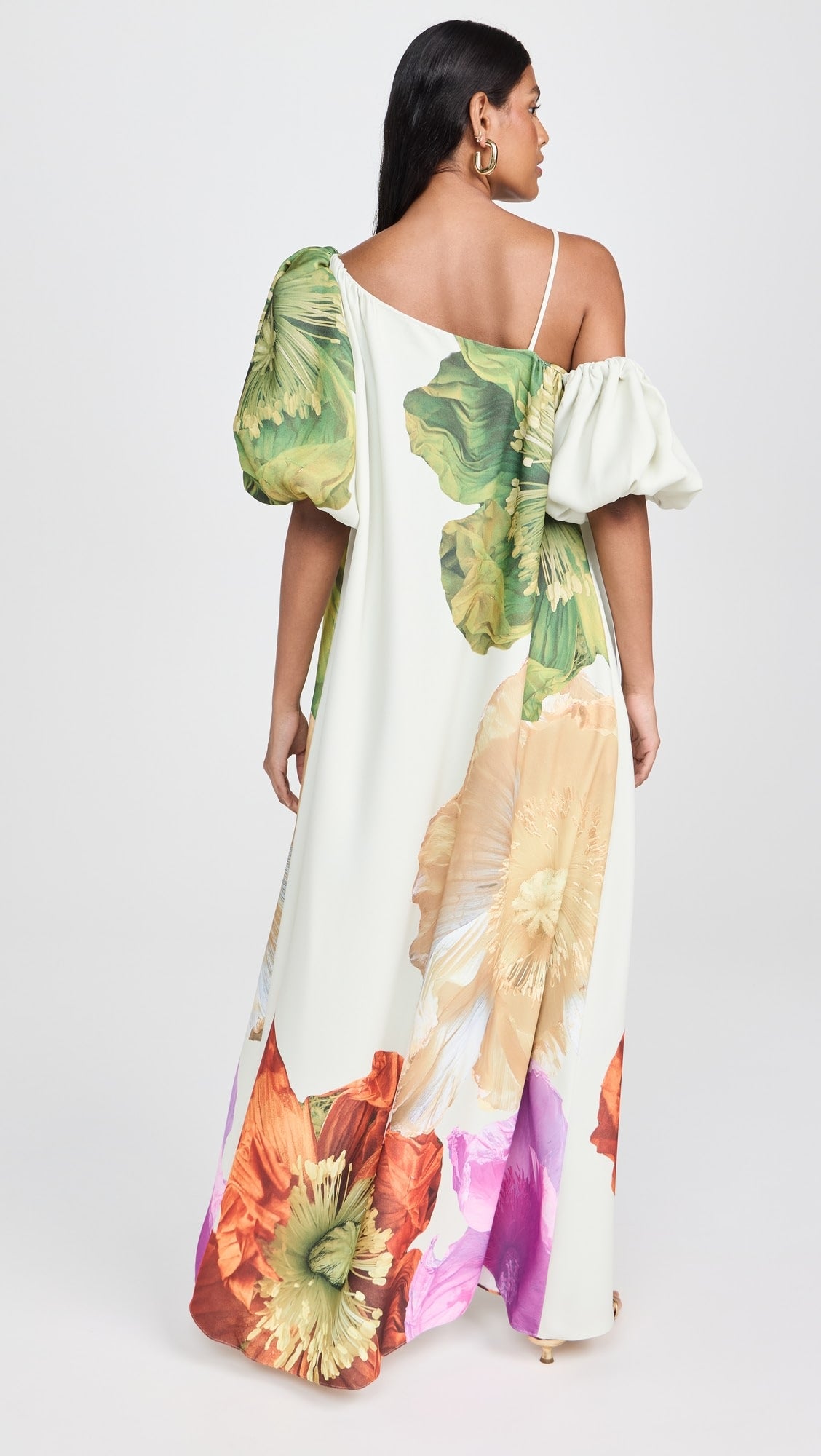 Vista traseira do vestido Hera com estampa floral, ombro único e corte fluido até o chão.